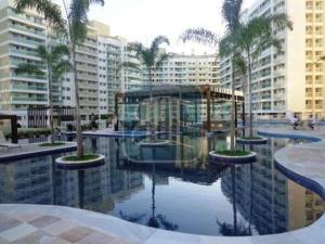 una piscina de agua con palmeras y edificios en Apartamento Sublime do Recreio, en Río de Janeiro