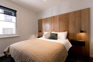 a bedroom with a large bed with a wooden headboard at 105 Mac Unique Apartments in Hobart