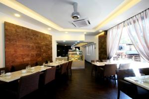 a dining room with tables and chairs and a brick wall at Hotel Ming Star in Kuala Terengganu