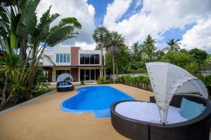 a swimming pool with a chair and a house at Villa Kanwara in Ao Nang Beach