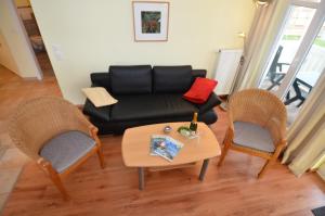 オストゼーバート・ゼリンにあるVilla Seerose - Appartement 17のリビングルーム(黒いソファ、椅子2脚付)