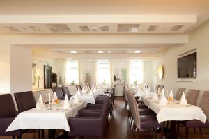 a row of tables and chairs in a restaurant at Zu den Drei Linden - Hotel & Restaurant in Wermelskirchen