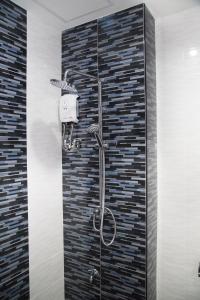 une douche dans une salle de bain avec un mur carrelé dans l'établissement Sirin Boutique, à Nakhon Ratchasima