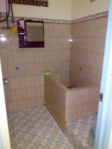 a bathroom with a tub and a tiled floor at Azalea Homestay in Batu
