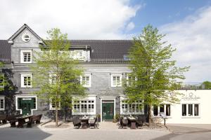 a large white building with benches in front of it at Zu den Drei Linden - Hotel & Restaurant in Wermelskirchen