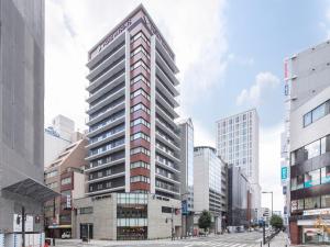 ein hohes Gebäude mitten in einer Stadt in der Unterkunft HOTEL MYSTAYS Midosuji Honmachi in Osaka