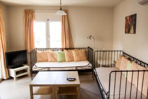 Argo Apartments Rethymno في مدينة ريثيمنو: غرفة معيشة مع أريكة وتلفزيون