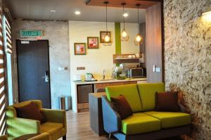 a living room with two chairs and a kitchen at Valya Hotel, Ipoh in Ipoh