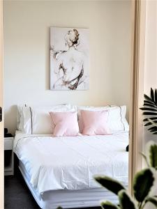 Un dormitorio con una cama con sábanas blancas y almohadas rosas. en ReadySet Apartments at Sentinel, en Melbourne 25 fotos más