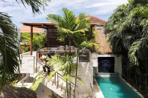 een huis met een zwembad en palmbomen bij Villa Bebek in Seminyak