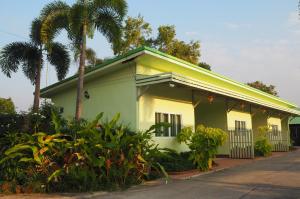 una casa amarilla con techo verde y palmeras en 555 Resort, en Udon Thani