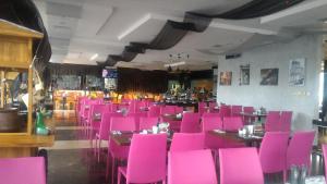 a dining room filled with pink chairs and tables at Neo Hotel Mangga Dua by ASTON in Jakarta