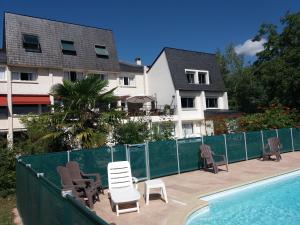 eine Gruppe von Stühlen und ein Pool vor einem Haus in der Unterkunft Hotel La Longue Vue in Gennes