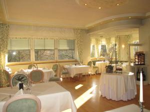 Schlosshotel Ingelfingen في Ingelfingen: مطعم بطاولات بيضاء وكراسي ونوافذ
