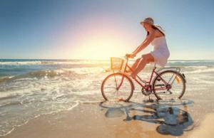 a woman riding a bike on the beach at Meeresblick Panorama Sauna Wlan Fi in Juliusruh
