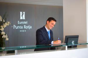 un hombre de traje sentado en una mesa con un portátil en Hipotels Eurotel Punta Rotja Spa-Golf, en Costa des Pins