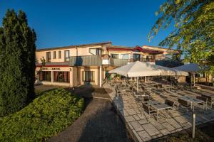 ein Restaurant mit Tischen und Sonnenschirmen vor einem Gebäude in der Unterkunft Les Terrasses Du Lac in Langogne