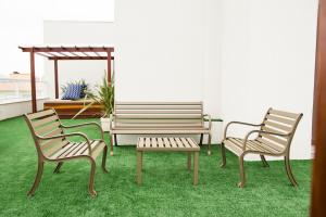 three chairs and a bench in a room with grass at Pousada Villa Di Enzo in Ubatuba