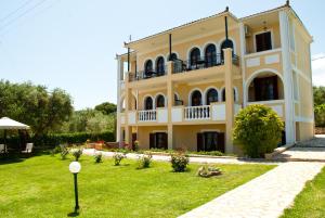 a large yellow building with a lawn in front of it at Amboula Beach Apartments in Tragaki