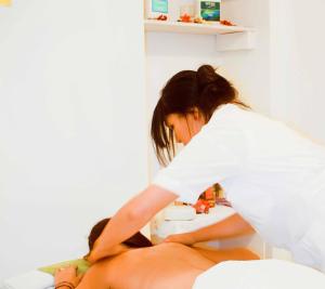 una mujer recibiendo un masaje de una mujer sentada en una cama en Napolitano Hotel, en Santo Domingo