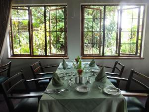 comedor con mesa, sillas y ventanas en Karula Hotel en White River