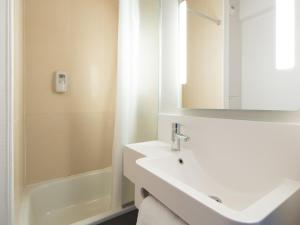 a bathroom with a sink and a shower and a mirror at B&B HOTEL Blois in Vineuil