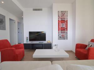 sala de estar con sillas rojas y TV en Belvilla by OYO Casa Frambuesa, en Los Montesinos