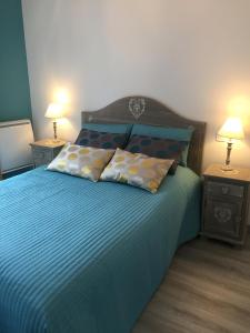 1 dormitorio con 1 cama con sábanas y almohadas azules en Les Meublés de Luchon - La Perle Bleue, en Luchon