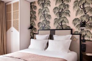 a bedroom with a bed with palm trees wallpaper at Hôtel Doisy - Orso Hotels in Paris