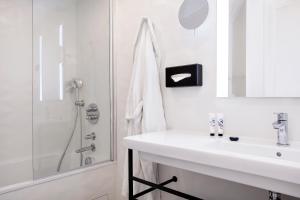 a white bathroom with a sink and a shower at Doisy Etoile - Orso Hotels in Paris