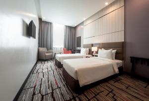 a hotel room with two beds and a chair at Promenade Hotel Bintulu in Bintulu