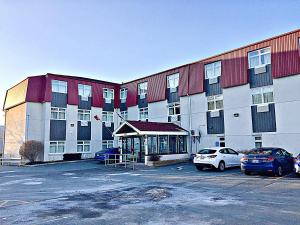 a large building with cars parked in a parking lot at Coastal Inn Dartmouth in Halifax
