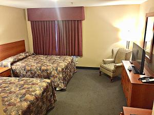 ein Hotelzimmer mit 2 Betten, einem Schreibtisch und einem Stuhl in der Unterkunft Coastal Inn Dartmouth in Halifax