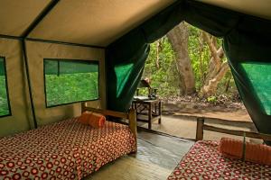 sypialnia w namiocie z łóżkiem i stołem w obiekcie Selous River Camp w mieście Kwangwazi