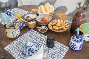 einem Holztisch mit Schalen mit Speisen und Platten in der Unterkunft Alfazema Cultural Bed and Breakfast in Arembepe