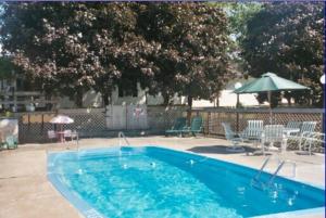 Pulaski的住宿－波特汽車旅館，蓝色游泳池配有椅子和遮阳伞