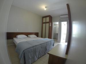 a bedroom with a bed and a table in it at Residencial Porto Farol in Salvador