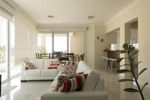una sala de estar con 2 sofás blancos y una mesa. en Mallorca Penthouse - cobertura com piscina privativa e vista pro mar, en Bombinhas