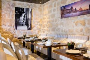 a restaurant with tables and chairs and a stone wall at Hôtel du Lion d'Or Louvre in Paris
