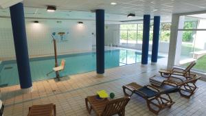 - une piscine avec des chaises et des tables dans un bâtiment dans l'établissement VVF Alsace Orbey Colmar, à Orbey