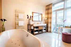 a bathroom with a tub and a sink and a mirror at Alden Suite Hotel Splügenschloss Zurich in Zurich