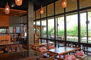 a restaurant with wooden tables and chairs and windows at SHYE Lithuania Homestay in Xinshe