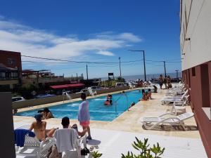 Un grupo de personas sentadas alrededor de una piscina. en Atlantico Hotel, en Villa Gesell