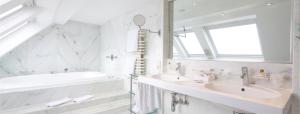 a white bathroom with two sinks and a tub at Hotel Approach in Knokke-Heist