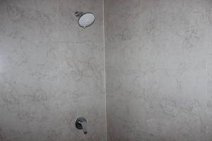 a shower with a stone wall with a shower head at Adi Bali Homestay in Uluwatu