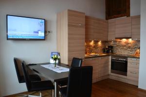 a kitchen with a table and a tv on the wall at Appartement Herzog in Saalfelden am Steinernen Meer