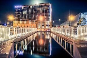 a building at night with a body of water at Mercure Cherbourg Centre Port in Cherbourg en Cotentin