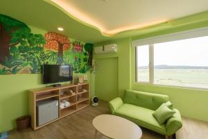 a green living room with a green couch and a television at Let's Play B&B 七桃旅宿 in Nanwan