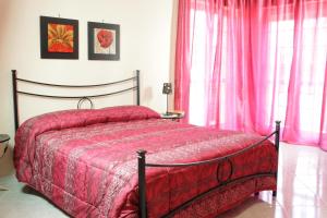 1 dormitorio con cama roja y cortinas rosas en Vesuvio Bed & Breakfast, en Scafati