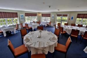 a dining room with white tables and chairs at Quorn Grange Hotel in Loughborough